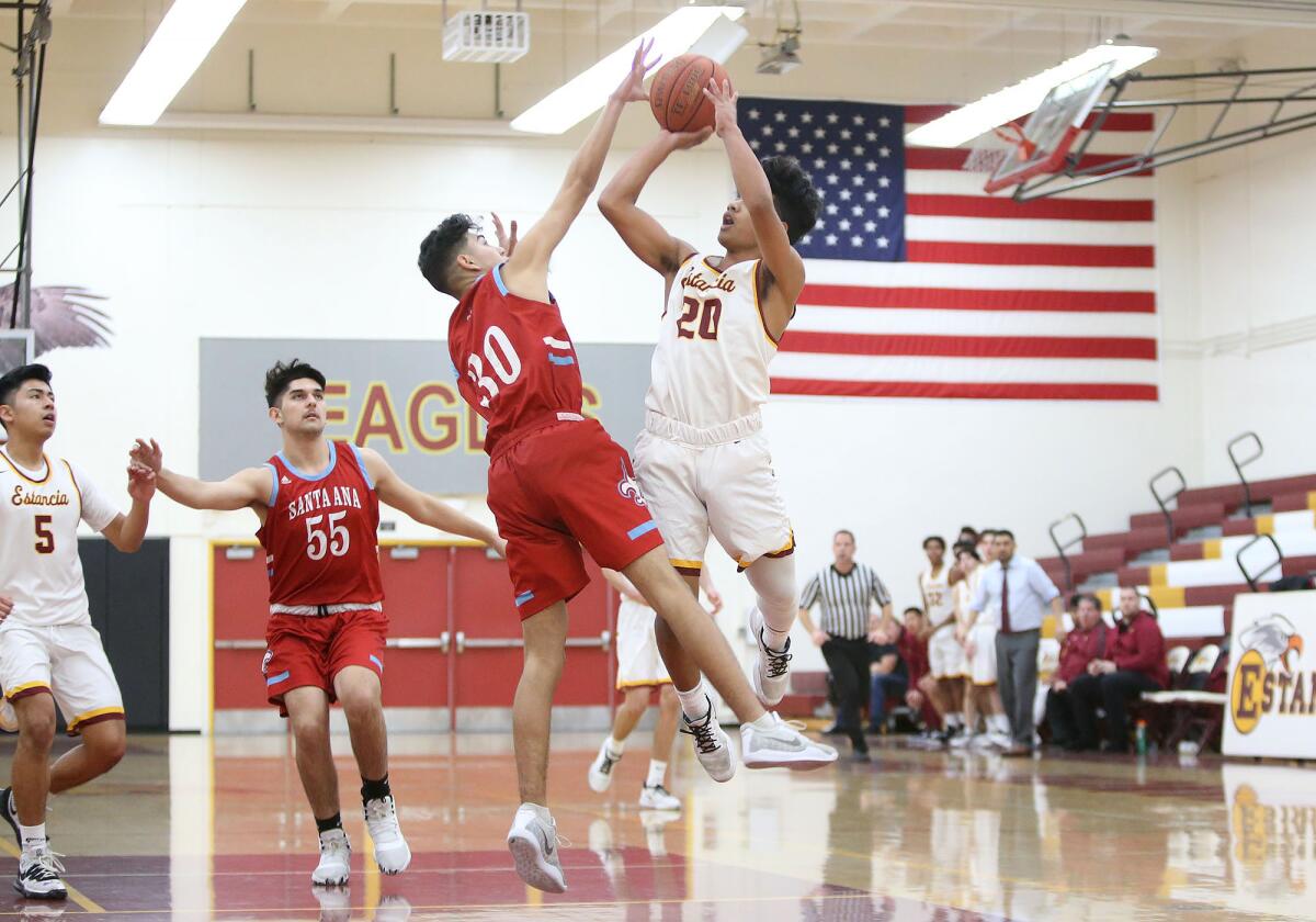 Estancia's Franky DeBrum (20) shoots a pull-up jumper as Santa Ana's Deaven Perez (30) attempts to block it during an Orange Coast League game on Wednesday.