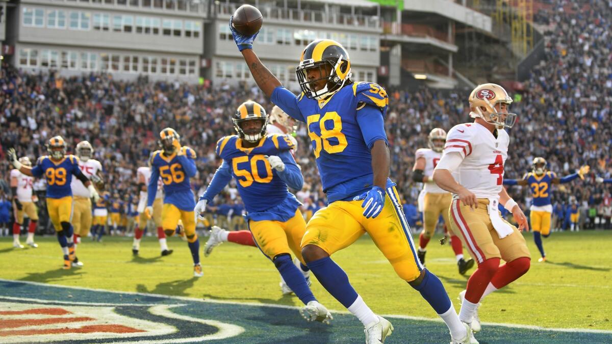 Rams linebacker Cory Littleton beats 49ers quarterback Nick Mullens (4) to the end zone while returning an interception for a touchdown in the second quarter at the Coliseum.