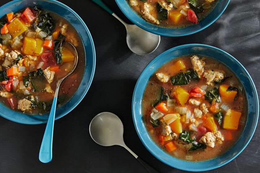 Bowls of broth brimming with chicken sausage and hearty vegetables.