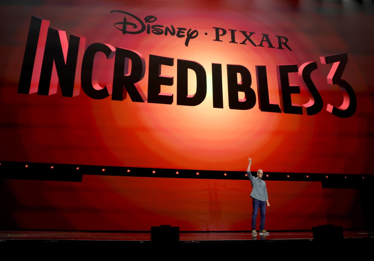 a man on stage standing in front of the 'Incredibles 3' logo