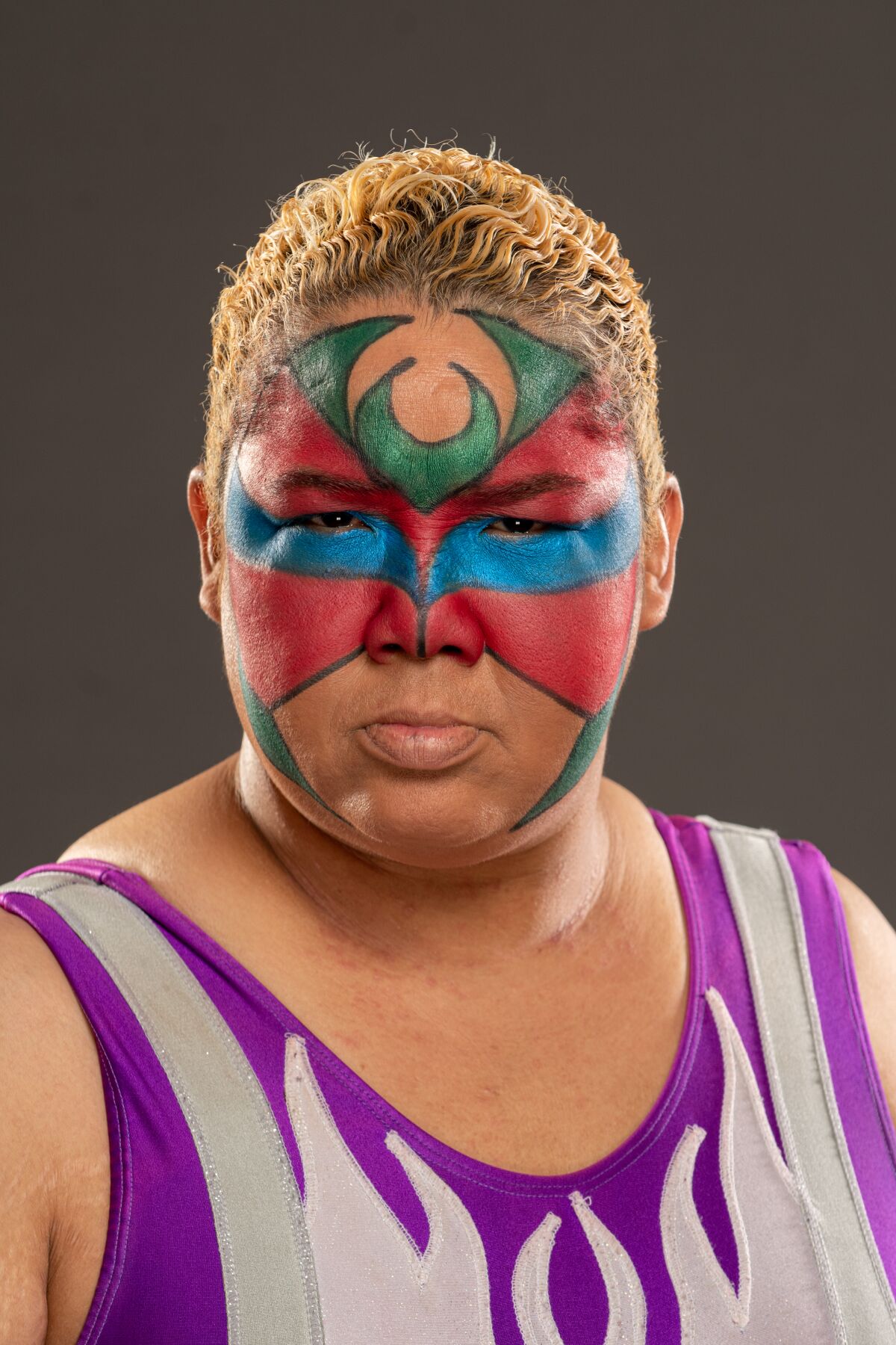 A wrestler with face paint poses for a portrait.