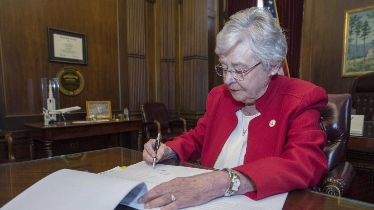 Alabama Gov. Kay Ivey signs a bill that virtually outlaws abortion in the state.