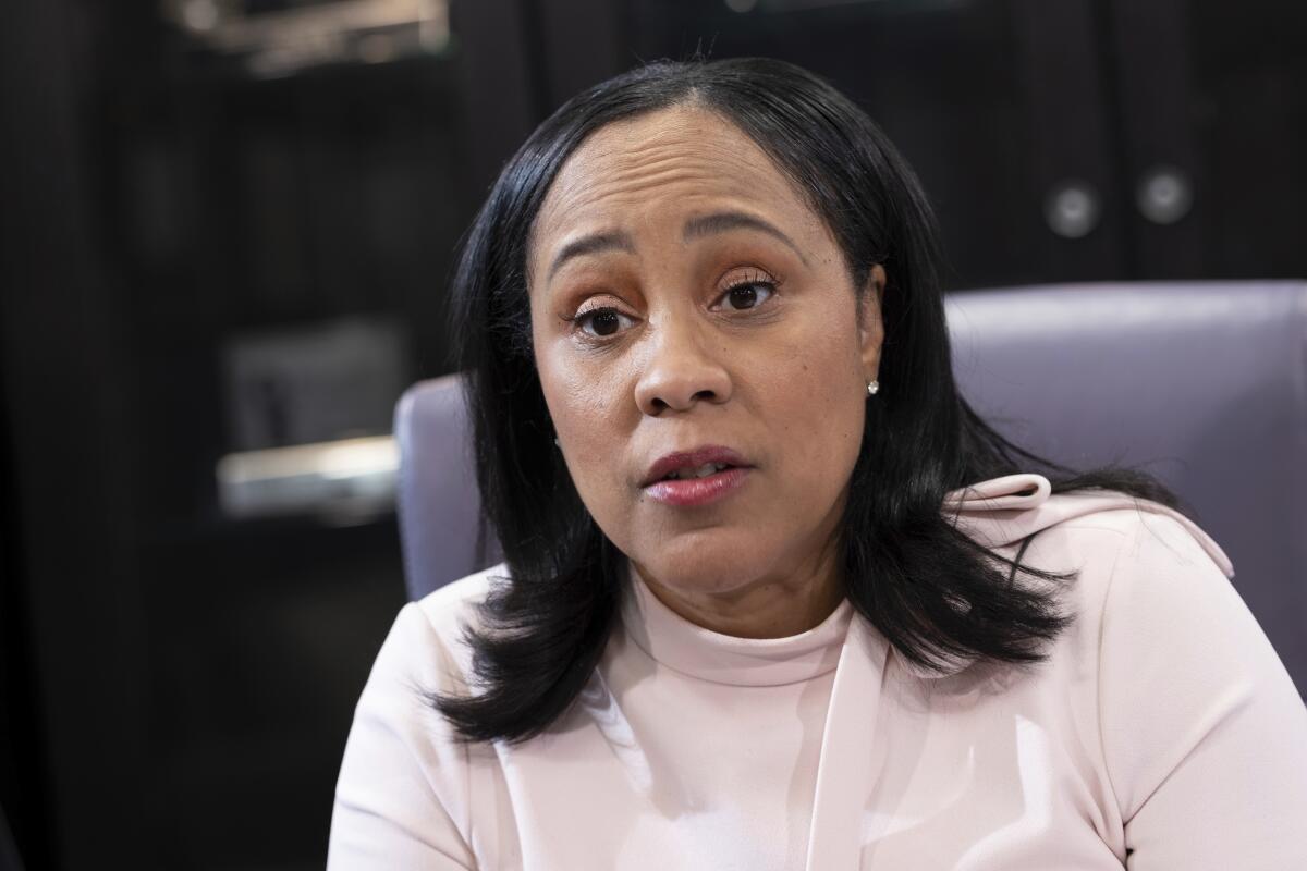 A woman pictured from the shoulders up, speaking while sitting in an office chair.