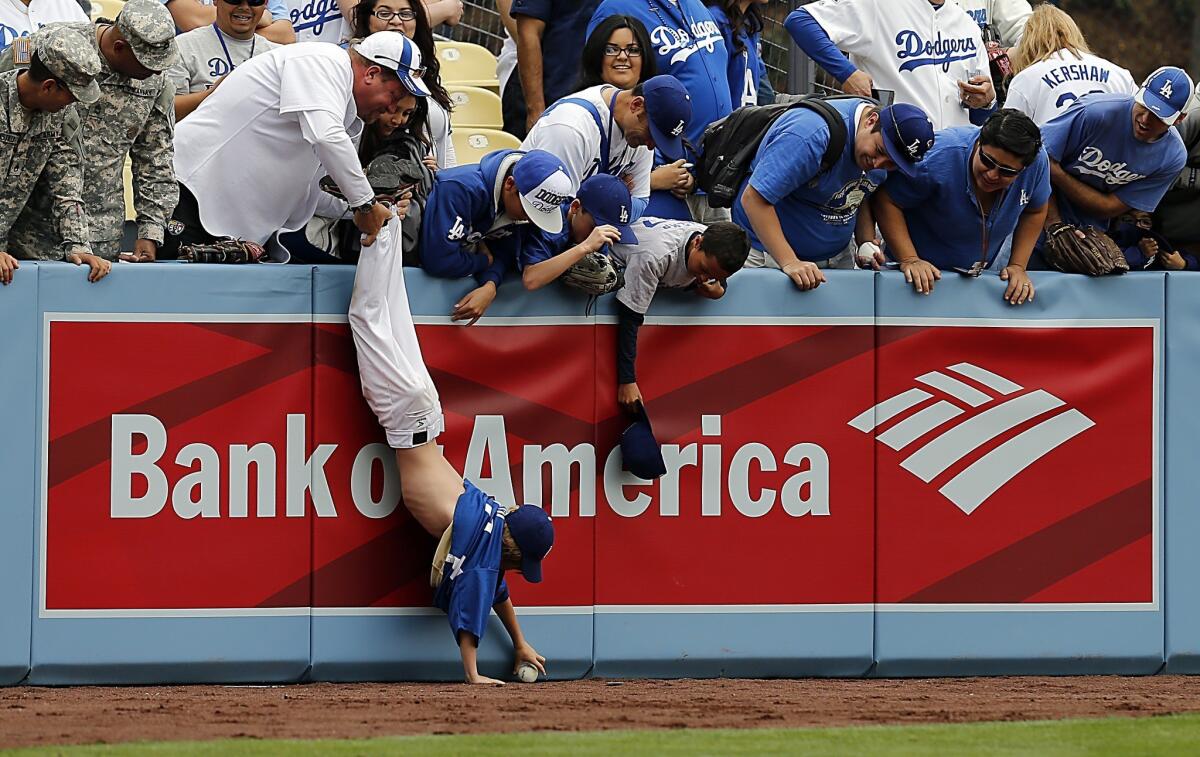 Exhuberant fans go after a foul ball as the Dodgers take batting practice before the season opener against the San Francisco Giants on Monday at Dodger Stadium.