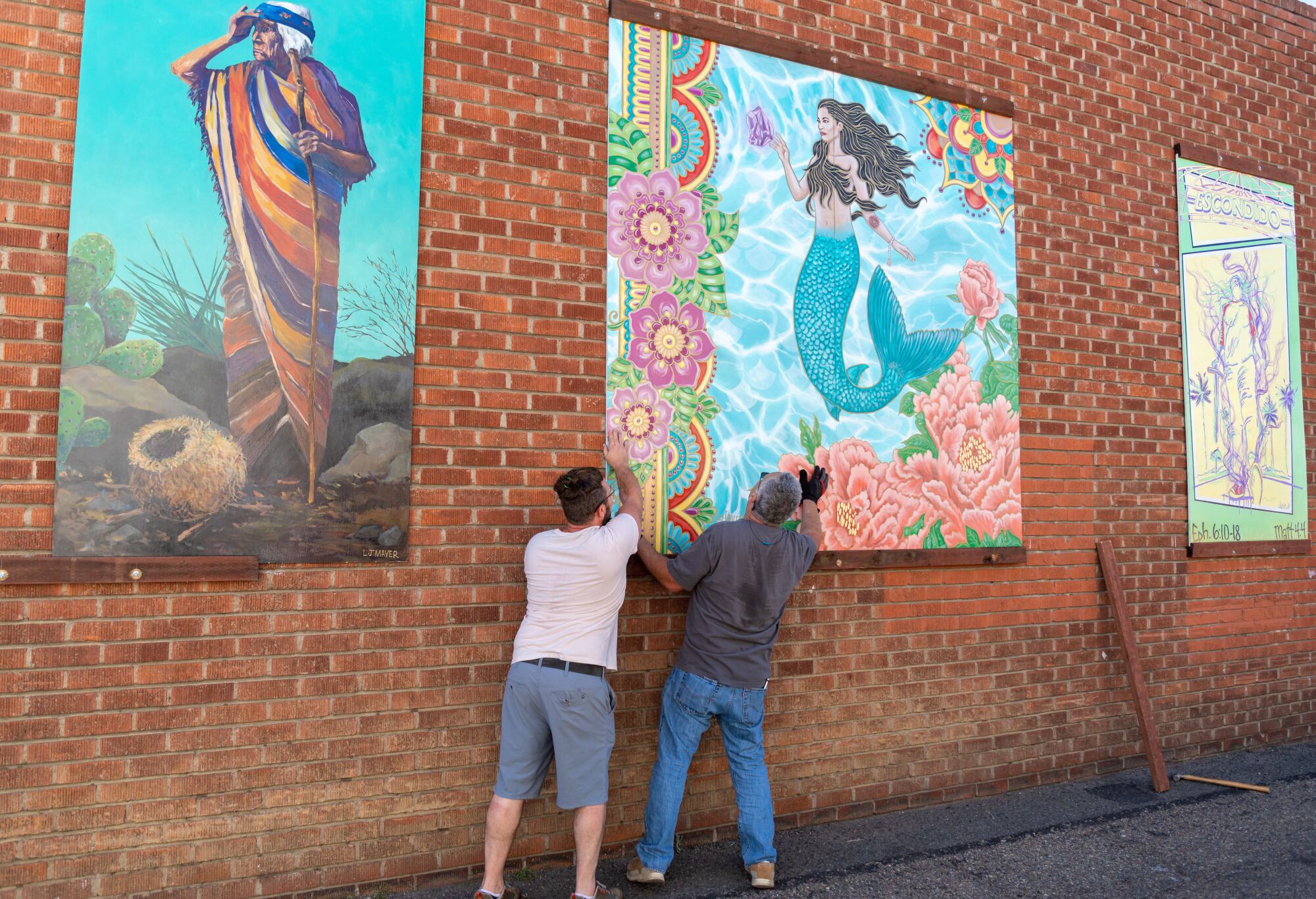 Escondido Art Association committee members Tristan Pittard and Dan Forster install artist mural panels