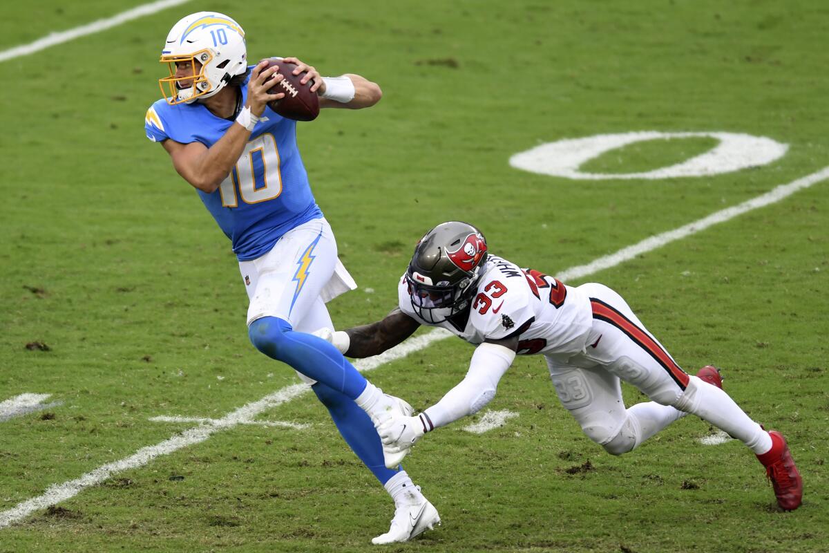 Chargers quarterback Justin Herbert eludes Tampa Bay Buccaneers free safety Jordan Whitehead during a game on Oct. 4.