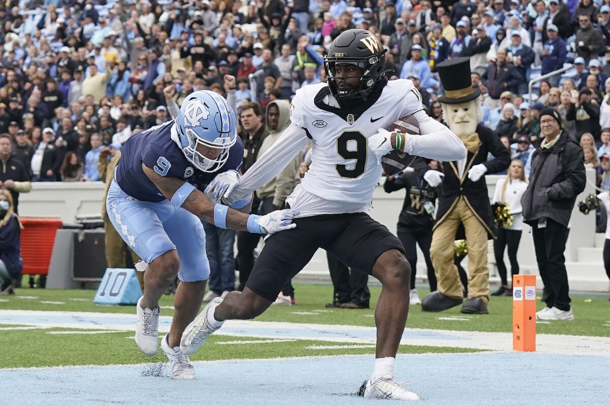 Wake Forest wide receiver A.T. Perry (9) scores a touchdown as North Carolina defensive back Cam'Ron Kelly (9) misses the tackle during the first half of an NCAA college football game in Chapel Hill, N.C., Saturday, Nov. 6, 2021. (AP Photo/Gerry Broome)