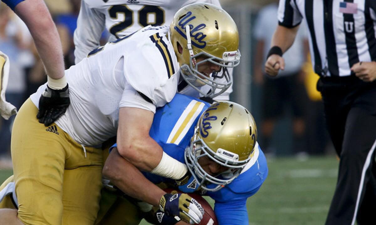 UCLA's Aaron Porter tackles running back James Jordon during a 2013 spring practice session. Porter, who moved from linebacker to running back last fall, is not presently enrolled at the university.