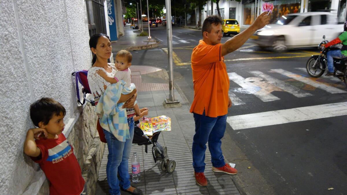 Leonardo Albornoz, an unemployed heavy equipment mechanic from Venezuela, stands with his family as he tries to sell candy for coins to passing motorists. "I'm being forced to beg because there is no work," he said.