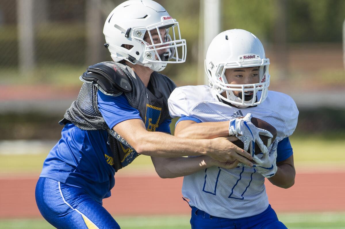 Fountain Valley quarterback Jimmy Russell hands the ball off to Nathan Le during practice on Aug. 8.