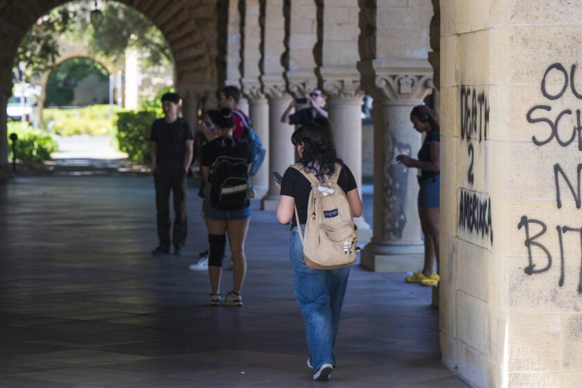 Students walk by graffiti near the office of the president at Stanford University in Palo Alto, Calif., Wednesday, June 5, 2024. Stanford University said people were arrested as law enforcement removed pro-Palestinian demonstrators who occupied a campus building early Wednesday that houses the university president and provost offices, with the school saying there was damage inside and outside the building. (AP Photo/Nic Coury)
