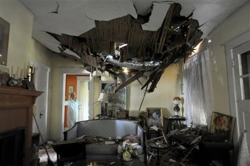 Frances Lukens looks at the tangle of boards and tree limbs piercing her living room ceiling in Lynchburg, Va. on Saturday, June 30, 2012 after a huge oak tree fell directly on the house during a storm the previous night. (AP Photo/The News & Advance, Parker Michels-Boyce)