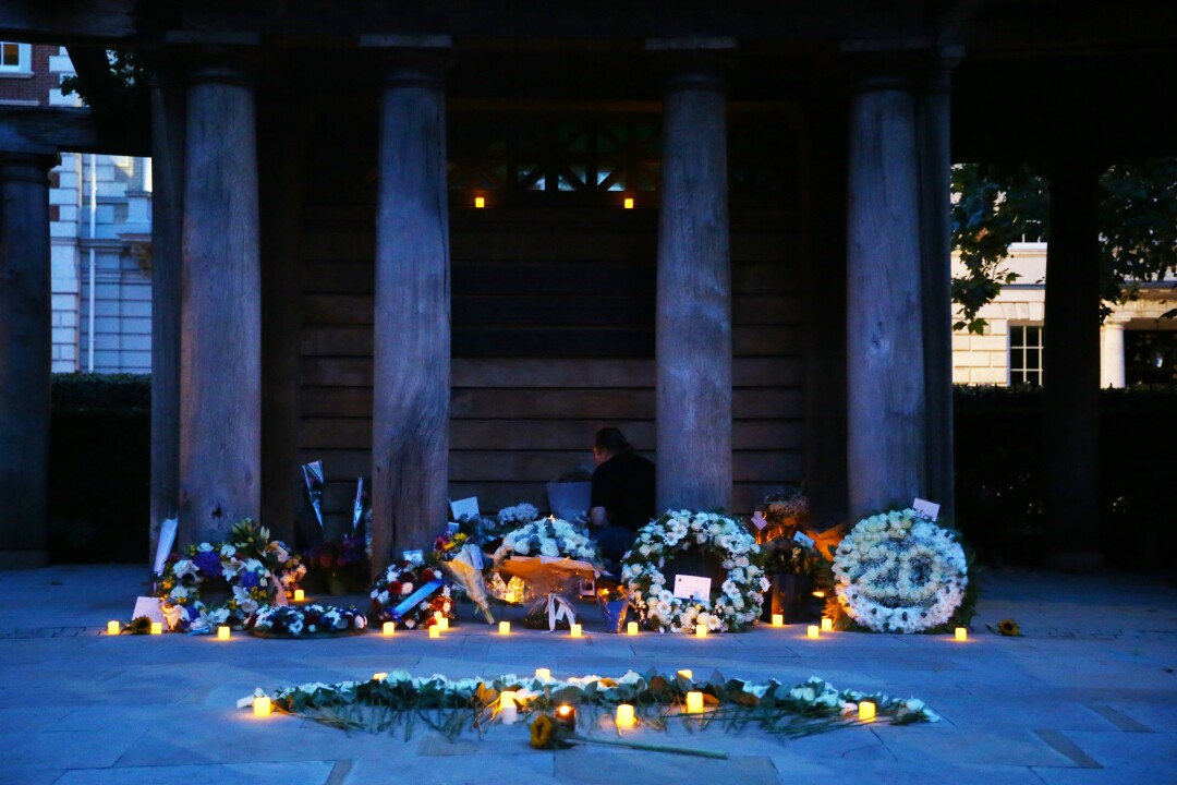 مردی در تاریخ 11 سپتامبر در لندن در میان تاج ها و شمع ها در Memorial Garden ادای احترام می کند