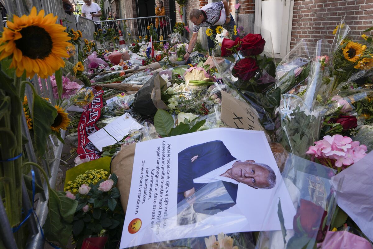 FILE - In this Thursday, July 8, 2021 file photo, a photo and floral tributes mark the spot where journalist Peter R. de Vries was shot in Amsterdam, Netherlands. The trial opens Monday, Oct. 18, 2021 of two men charged with murder in the killing of Dutch crime reporter Peter R. de Vries, who was gunned down in the center of Amsterdam, a brazen attack that sent shockwaves through the Netherlands. (AP Photo/Peter Dejong, File)