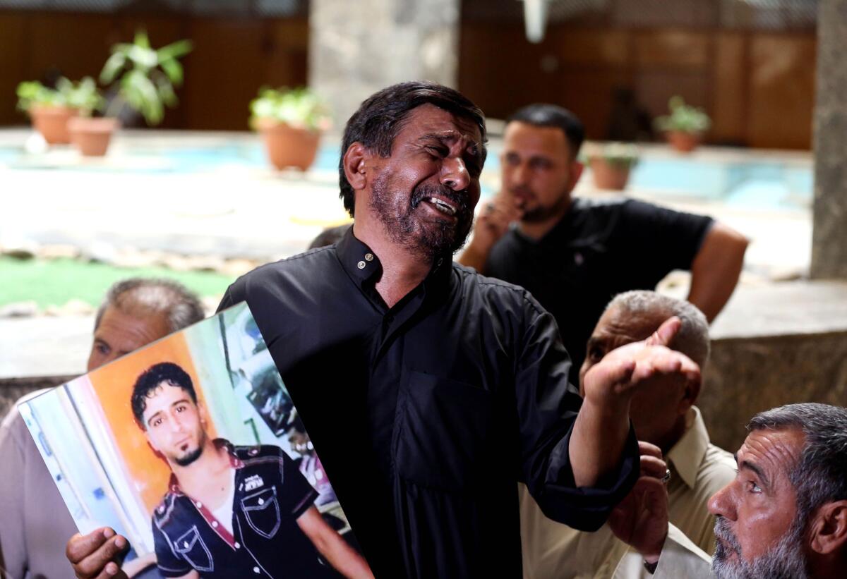 An Iraqi father holds a poster of his slain son during the July 8 session of a trial of suspected Islamic State members accused of taking part in the killings of 1,700 government soldiers in Tikrit in June 2014.