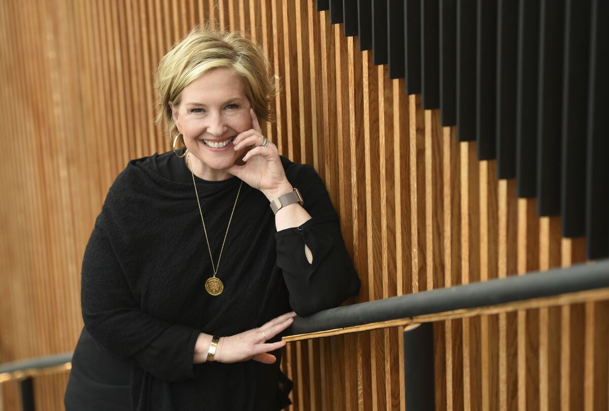 Brené Brown posing in a black shirt and gold necklace