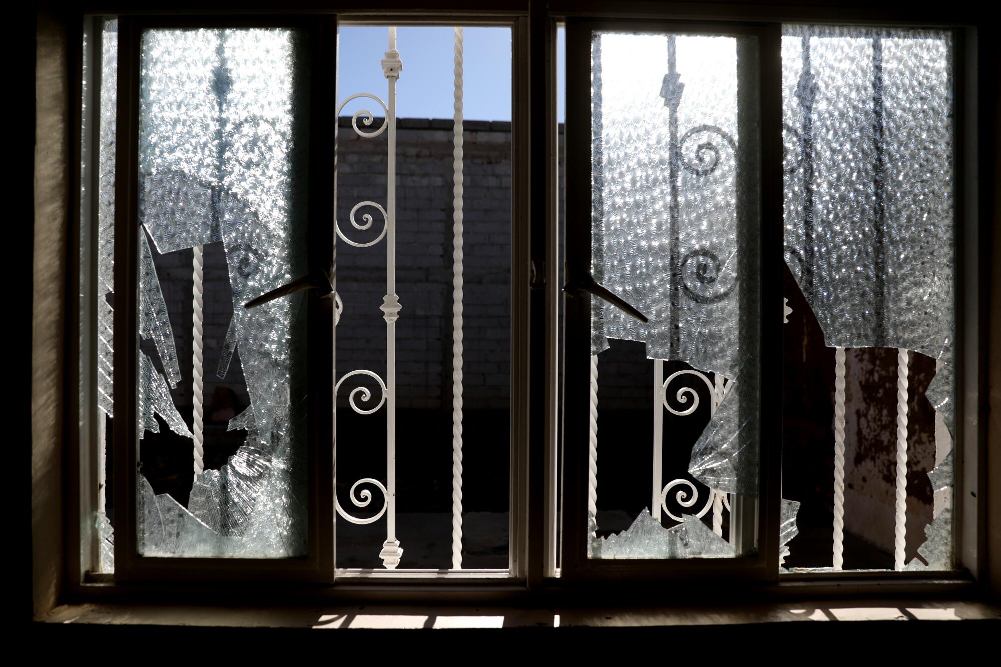 Shattered windows with decorative wrought iron outside them 