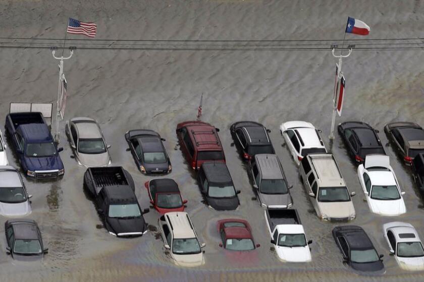 This combo of file photos shows flooded cars near the Addicks Reservoir as floodwaters from Tropical Storm Harvey rise in Houston on Aug. 29, 2017, at top, and vehicles in a car dealership lot sit surrounded by floodwaters in the aftermath of Hurricane Katrina, Sept. 10, 2005, in New Orleans, at bottom. (AP Photo/David Phillip, File)
