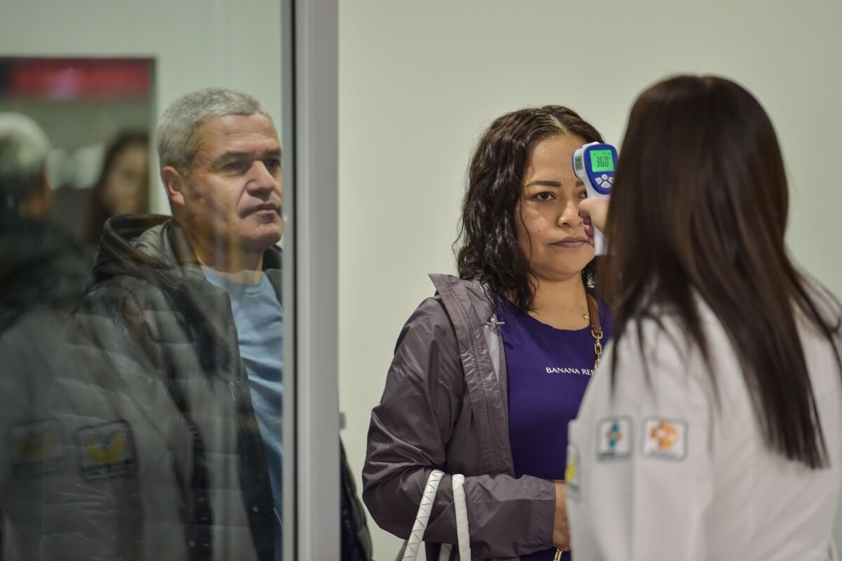 International health personnel checks the temperature of a passenger on March 13 at the Benito Juarez International Airport in Mexico City as a preventive measure in the face of the global coronavirus pandemic.