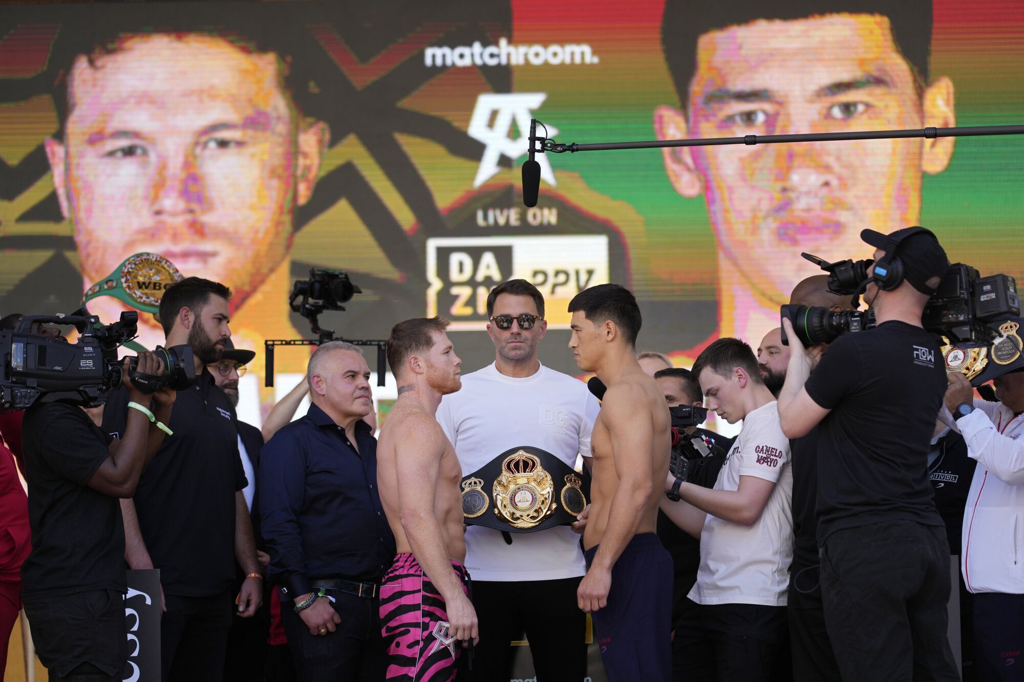 Canelo Álvarez and Dmitry Bivol face off next to promoter Eddie Hearn during a ceremonial weigh-in Friday in Las Vegas.