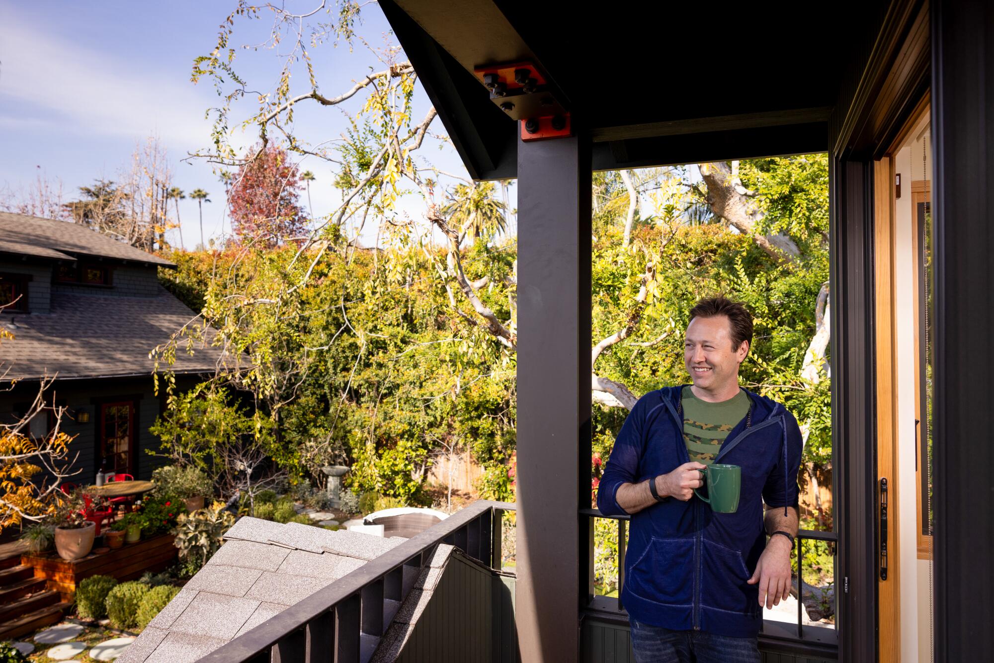 Russell Brown stands on his balcony with his 1912 Craftsman home in view. 