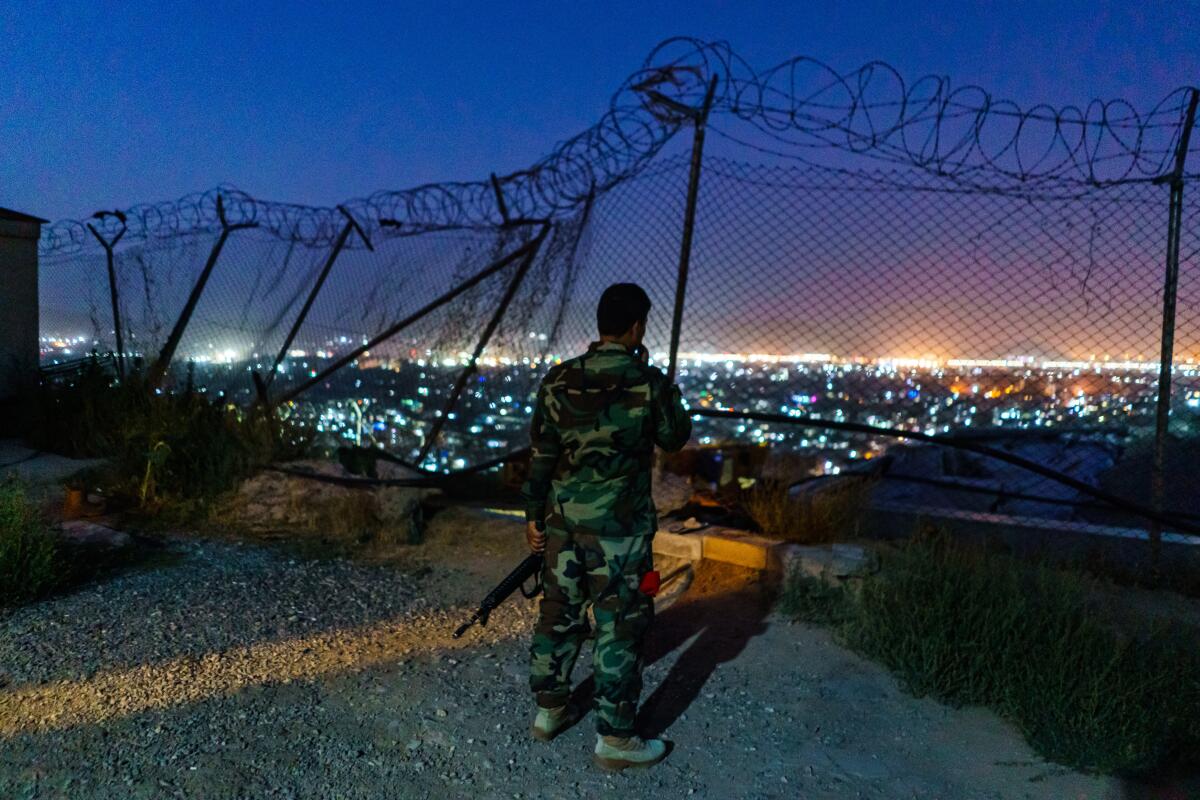 Afghan soldiers at post overlooking city lights  