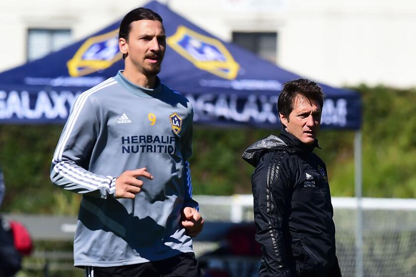 Guillermo Barros Schelotto, head coach of the LA Galaxy of the MLS, watches his players during a training session as Galaxy forward Zlatan Ibrahimovic runs past on February 22, 2019 in Carson, California. - From Buenos Aires to Los Angeles, without stops. From Boca to Galaxy, without safety net. Losing the final of the Libertadores against his archrival River to try to resurrect the most honored franchise in MLS history, Guillermo Barros Schelotto has never been afraid of the challenges. (Photo by Frederic J. BROWN / AFP)FREDERIC J. BROWN/AFP/Getty Images ** OUTS - ELSENT, FPG, CM - OUTS * NM, PH, VA if sourced by CT, LA or MoD **
