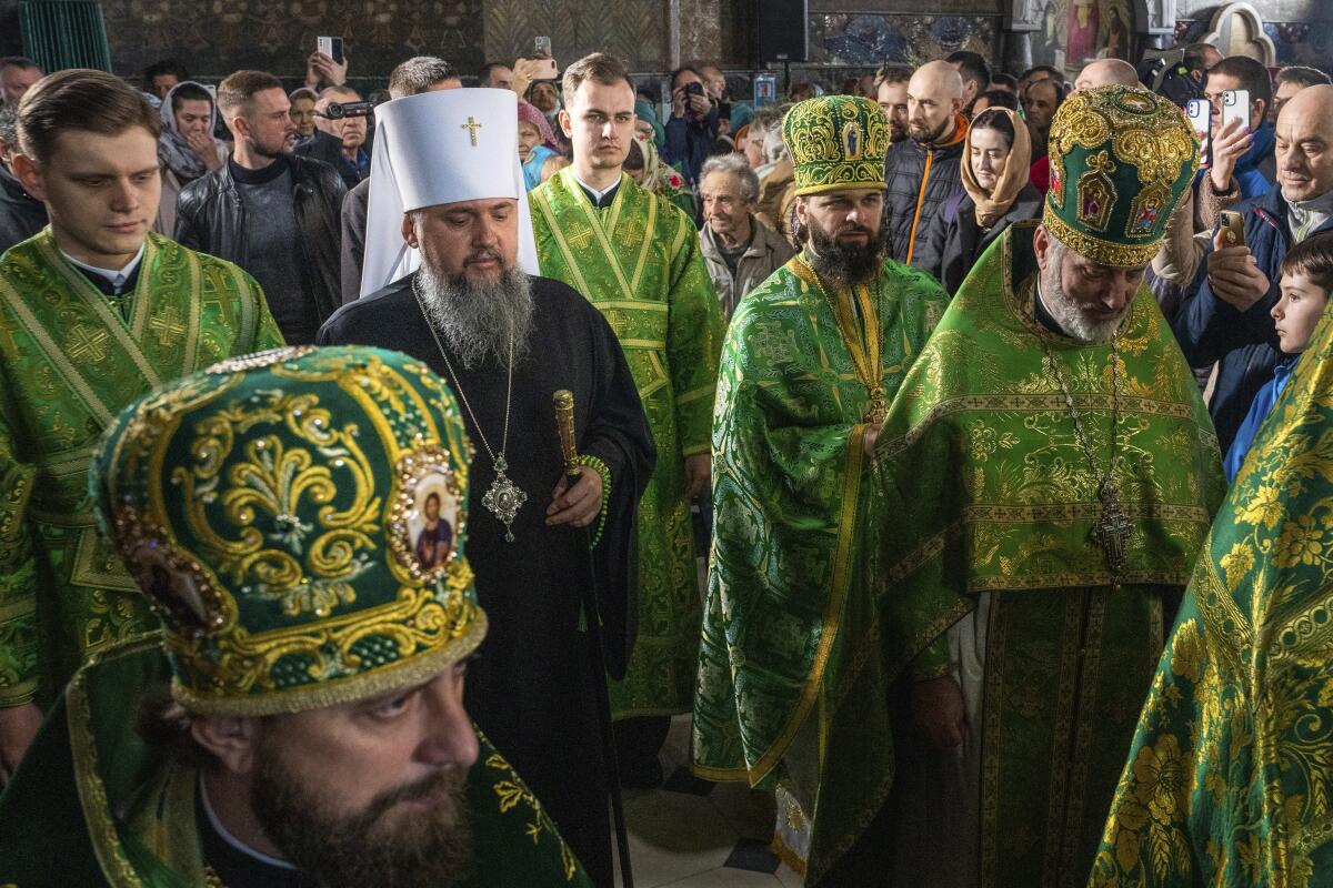 Orthodox Church of Ukraine officials, many clothed in green, celebrate Palm Sunday.