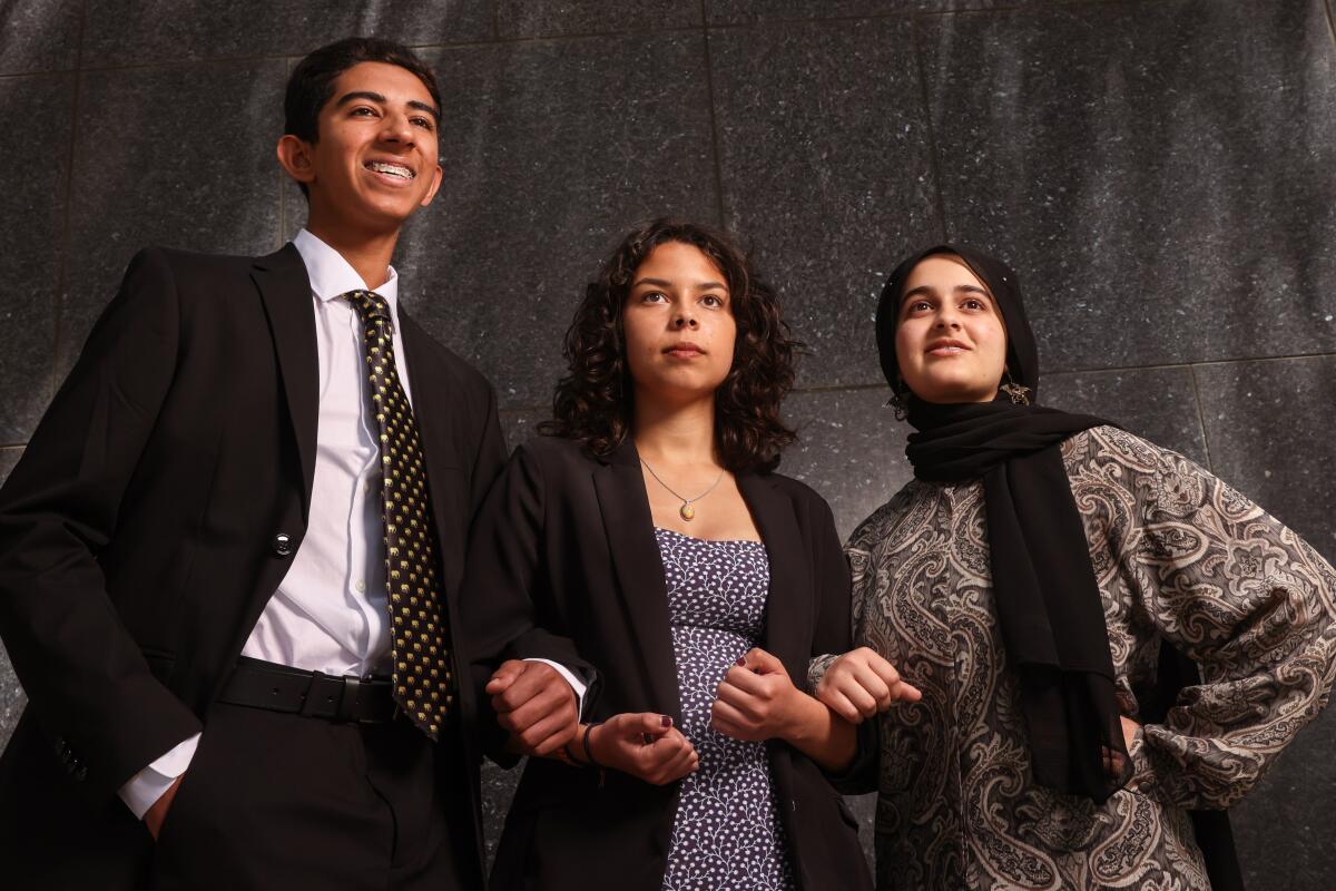 Three teenagers in professional clothing are photographed outside a courthouse in Los Angeles.