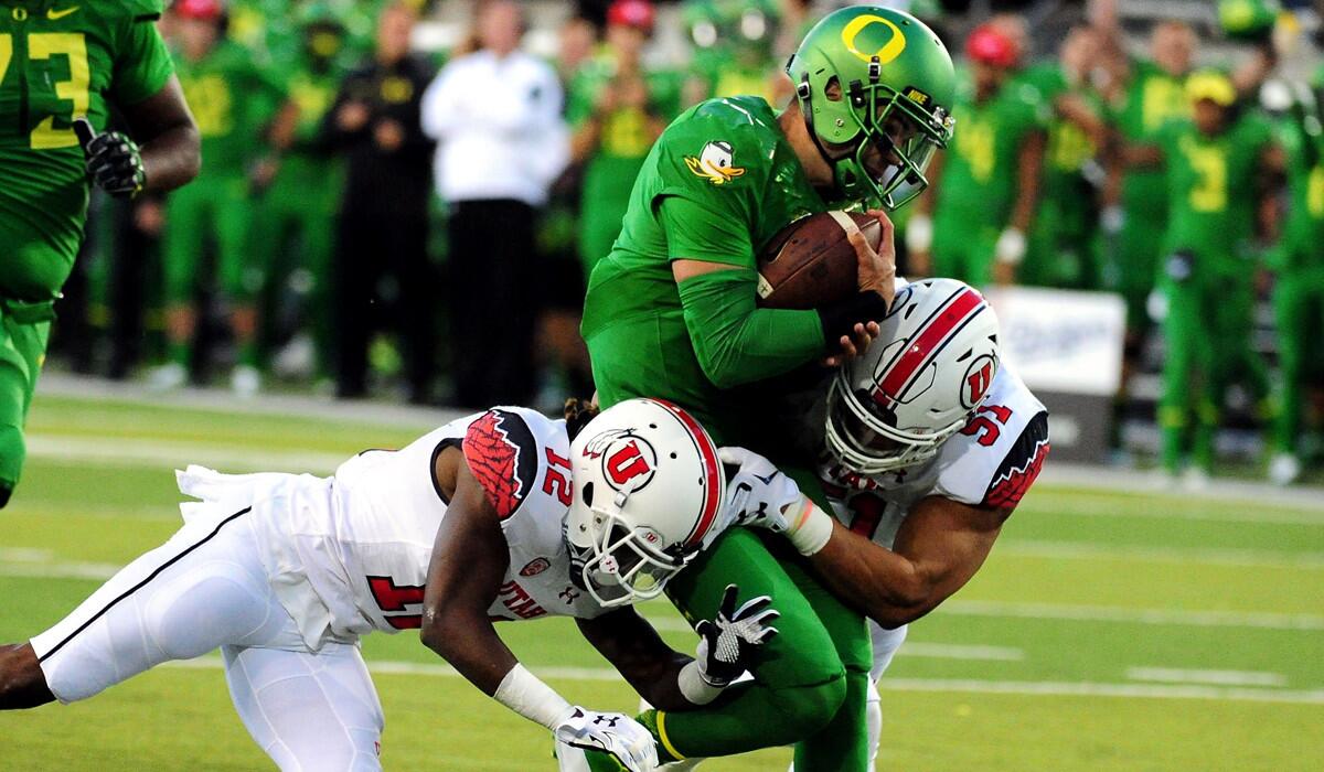 Oregon's quarterback Jeff Lockie, center, is tackled by Utah's defensive back Justin Thomas, left, and defensive end Jason Fanaika during a game on Saturday.