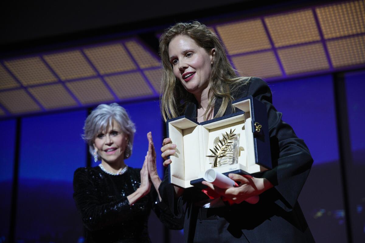 'Anatomy of a Fall' director Justine Triet holds the Palme d'Or as presenter Jane Fonda looks on at Cannes.
