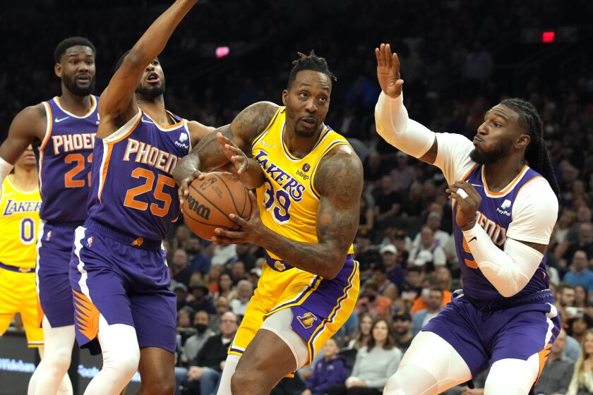 Los Angeles Lakers center Dwight Howard (39) drives between Phoenix Suns forward Mikal Bridges (25) and forward Jae Crowder, right, during the first half of an NBA basketball game Tuesday, April 5, 2022, in Phoenix. (AP Photo/Rick Scuteri)