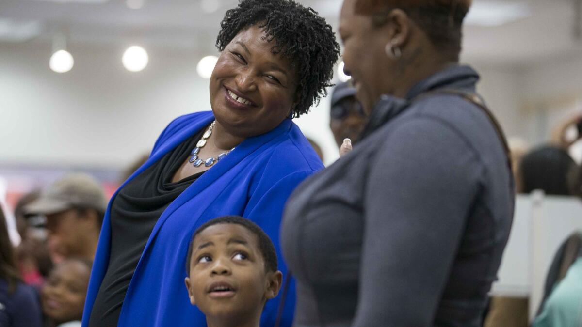 A voter speaks with gubernatorial candidate Stacey Abrams, left, as they wait in line for their ballots during early voting at a mall in Decatur, Ga.