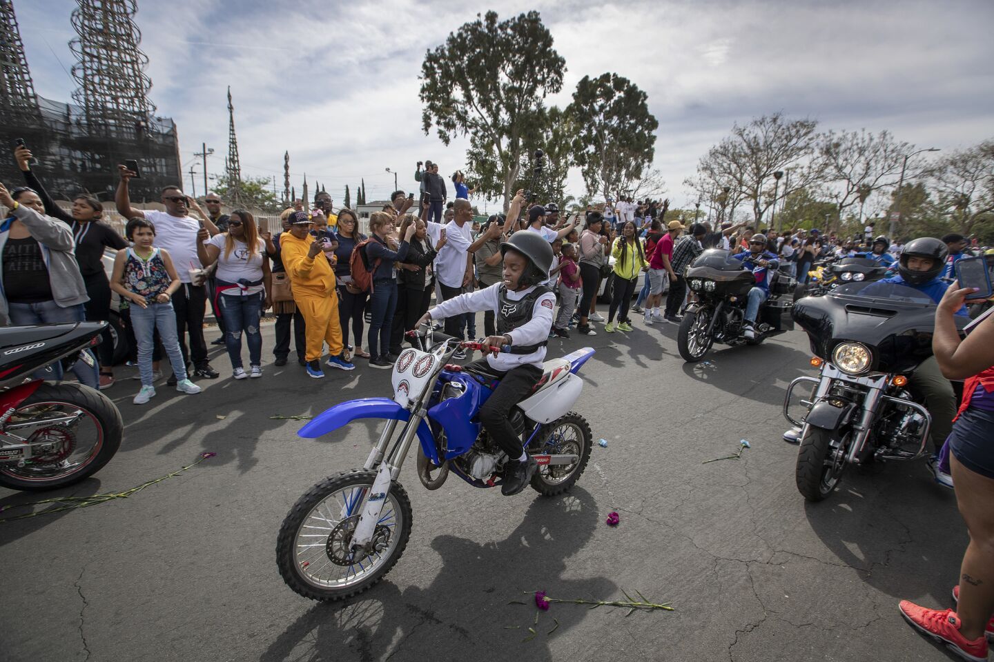 A child rides a dirt bike in the procession following the hearse in Watts.