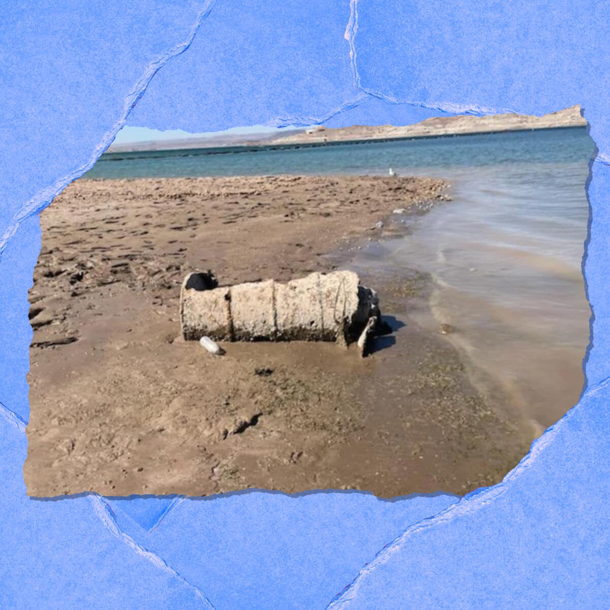 A rusted barrel is seen on a muddy lakeshore.