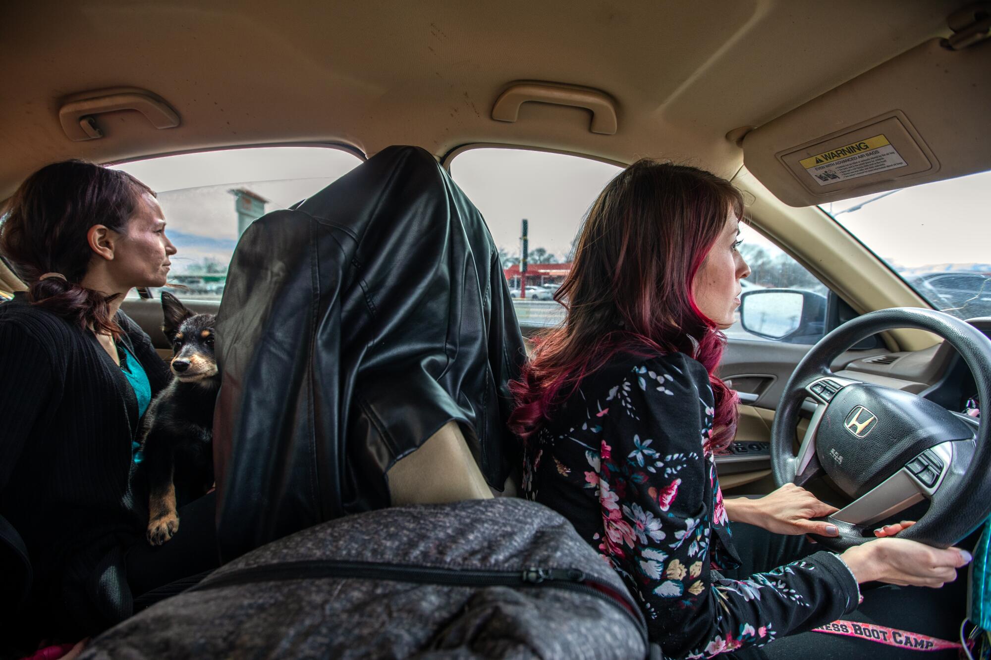 A woman sits in a backseat as another woman drives