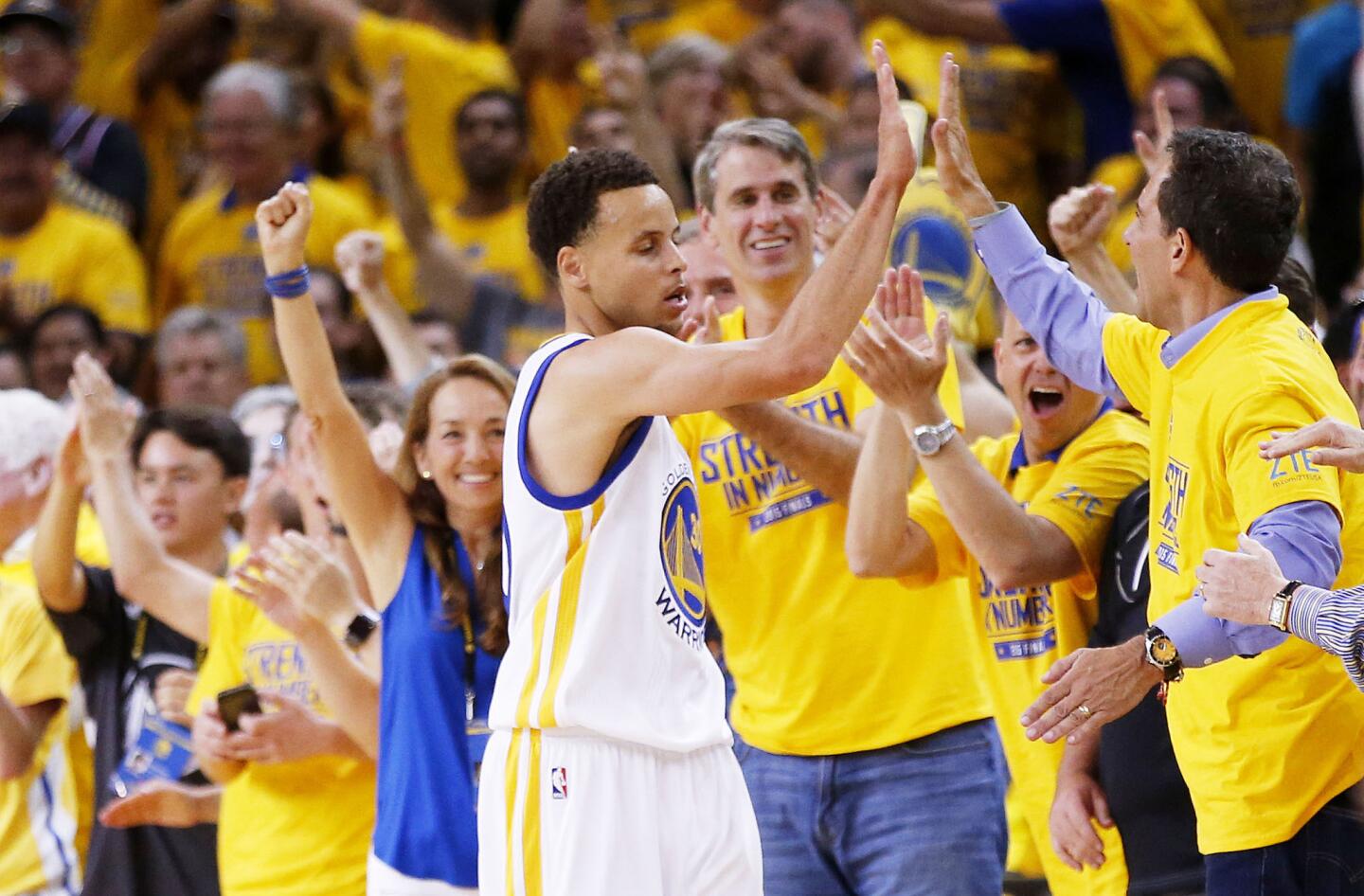 Warriors guard Stephen Curry celebrates with fans after making a shot against the Cavaliers in the fourth quarter of Game 5 of the NBA Finals on Sunday evening in Oakland.