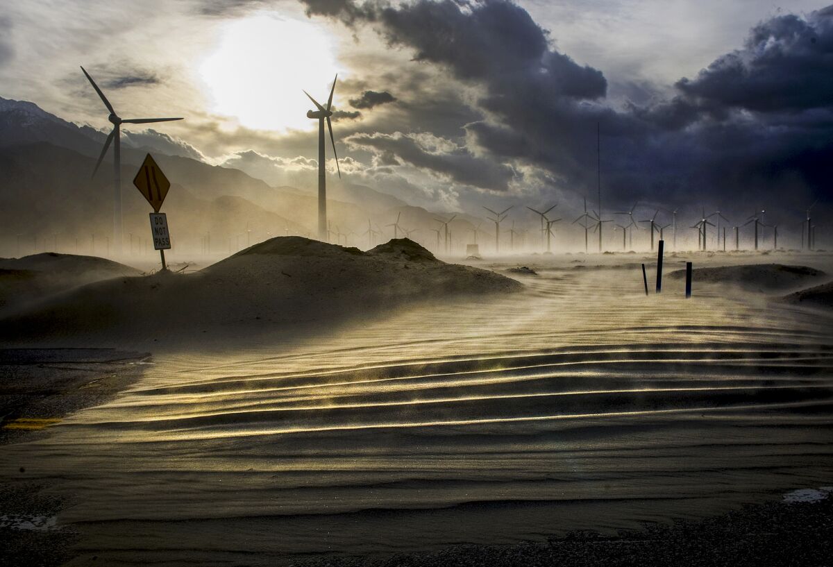 Gusty winds blow sand onto a Palm Springs road near the wind turbines in the San Gorgonio Pass.