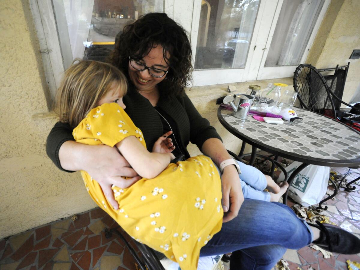 Sarah Clemente snuggles with daughter Penelope Clemente, 6, at a table