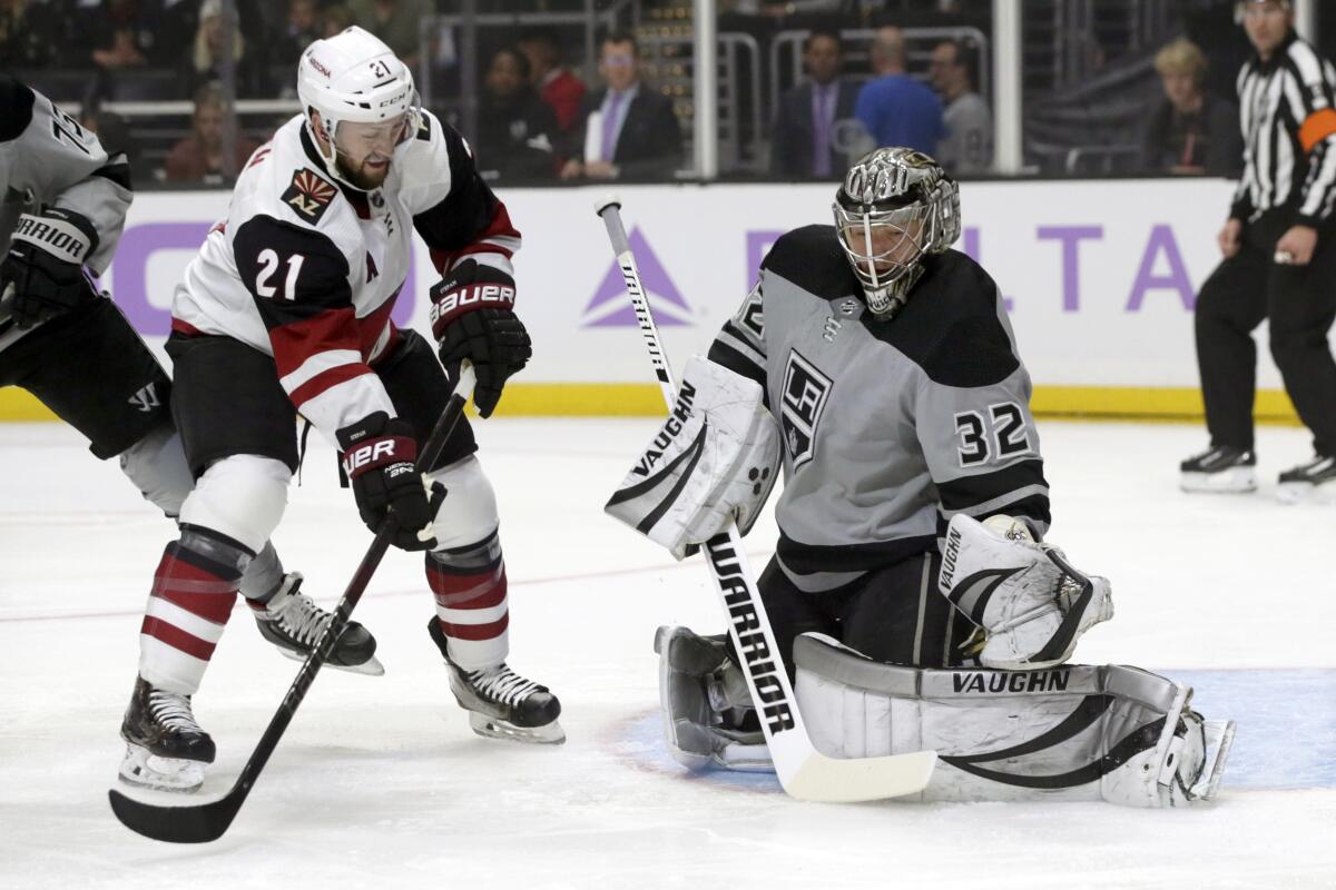 Kings goalie Jonathan Quick, right, catches the puck as Arizona Coyotes center Derek Stepan, left, watches during the first period on Saturday at Staples Center.