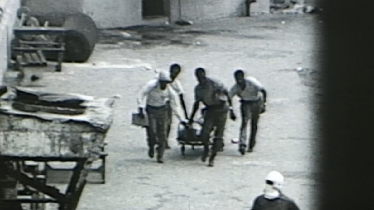 A black-and-white still of people pulling a cart 