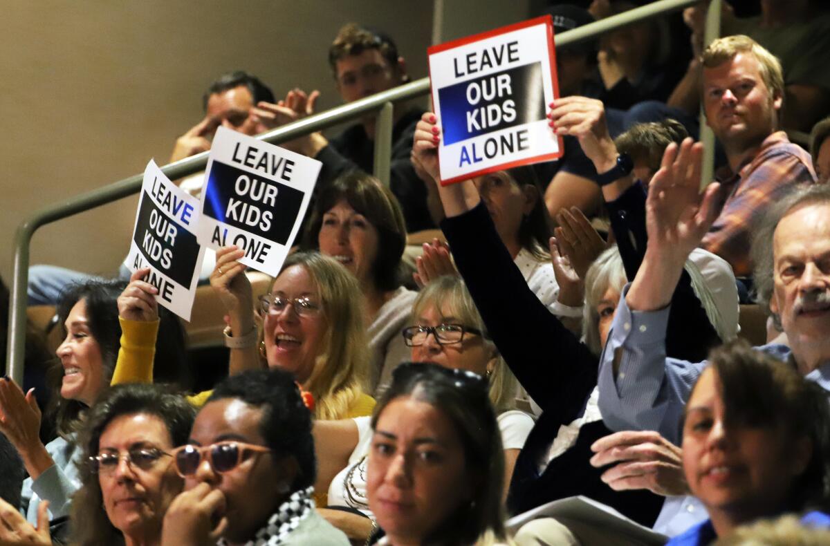 Huntington Beach residents cheer and hold signs during a October 2023 City Council meeting.