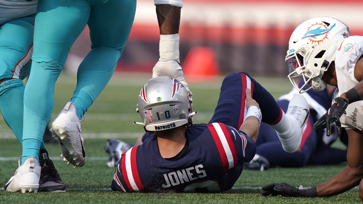 New England Patriots quarterback Mac Jones is tapped on the helmet after being sacked by the Miami Dolphins during the first half of an NFL football game, Sunday, Sept. 12, 2021, in Foxborough, Mass. (AP Photo/Steven Senne)