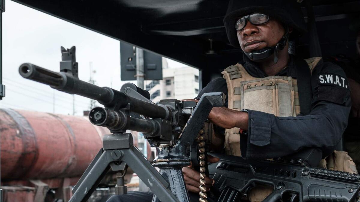 A Nigerian police SWAT member sits at the entrance of a vote counting center in Port Harcourt, Nigeria, on Feb. 26, 2019. Dozens have been killed in election-related violence.
