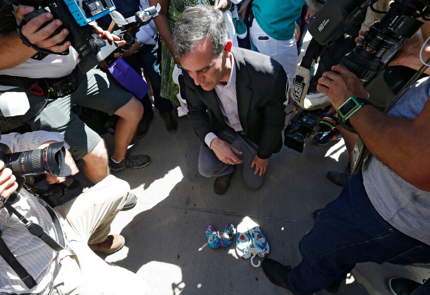 Mayor Eric Garcetti places a child's shoes next the border gate across from one of the tent cities along the United States-Mexico border at the Tornillo Port of Entry in Tornillo, Texas.