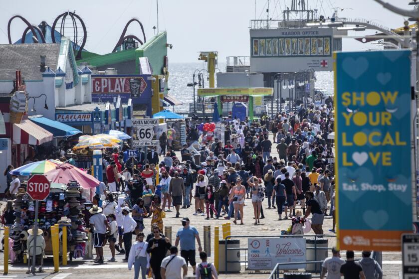 SANTA MONICA, CA - APRIL 05: Visitors stroll along the Santa Monica Pier on Monday, April 5, 2021 as Los Angeles County entered the less strict orange tier allowing more places to open and inviting more people to venture outdoors. Photographed in Santa Monica Pier in Santa Monica, CA. (Myung J. Chun / Los Angeles Times)