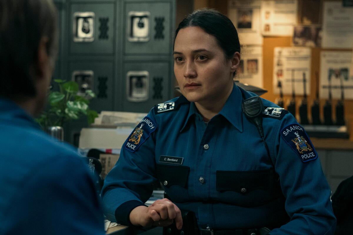 Lily Gladstone in a blue law-enforcement uniform.