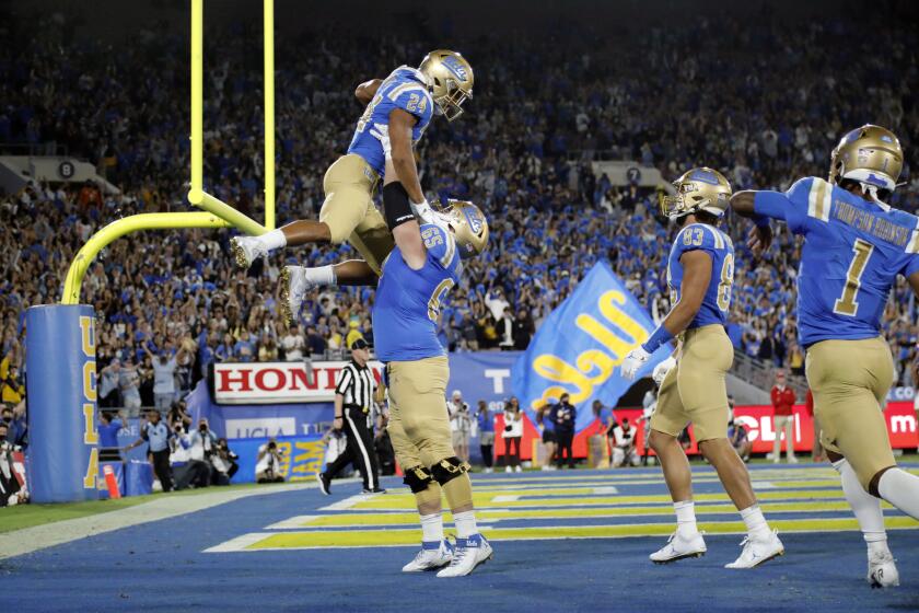 PASADENA, CA - SEPTEMBER 18, 2021: UCLA Bruins offensive lineman Paul Grattan (65) lifts up UCLA Bruins running back Zach Charbonnet (24) after Charbonnet scored in the first half against Fresno State at the Rose Bowl on September 18, 2021 in Pasadena, California.(Gina Ferazzi / Los Angeles Times)
