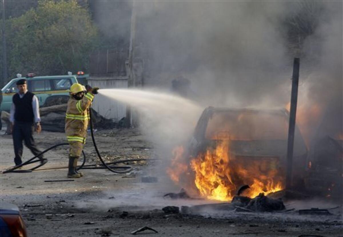 A firefighter tries to extinguish a fire after a car bomb attack in Baghdad, Iraq, Tuesday, Dec. 15, 2009. A series of car bombs ripped through downtown Baghdad near the heavily fortified Green Zone. (AP Photo/Hadi Mizban)