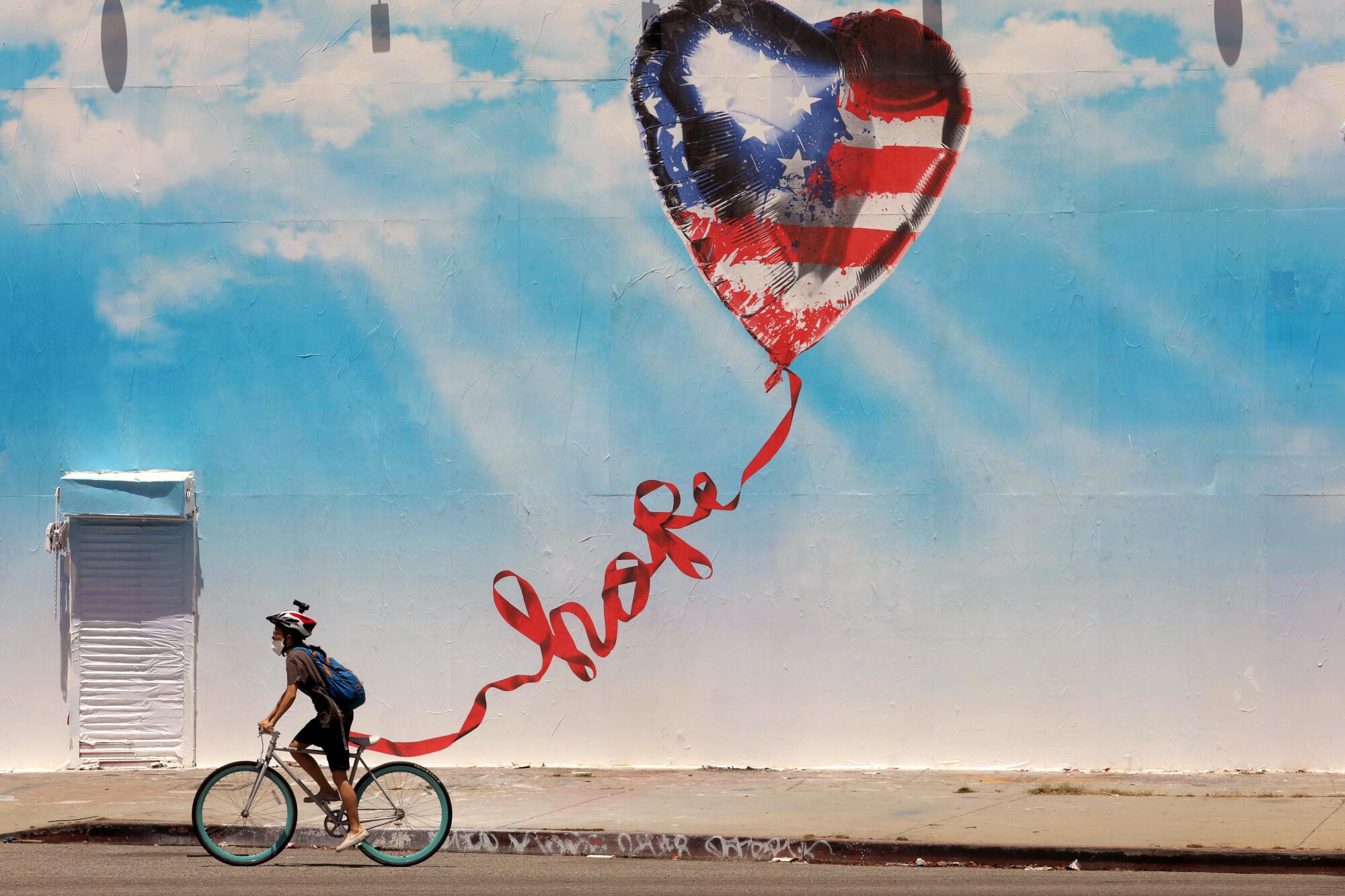 A bicyclist rides past a mural in Los Angeles.